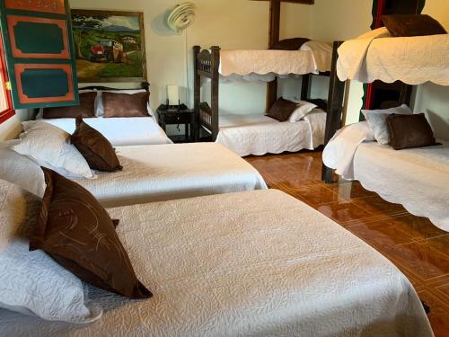 a room with four bunk beds with white sheets at Finca Hotel la Manuela in Armenia