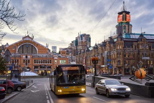 a yellow bus driving down a city street with cars at Big Jacuzzi , Sauna , Khreshchatyk apartments in Kyiv