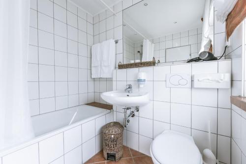 biała łazienka z umywalką i toaletą w obiekcie Gasthaus Spieker w mieście Hövelhof