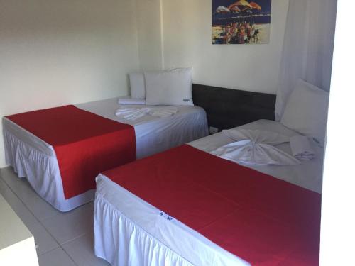 two beds in a hotel room with red and white at Nannai Beira Mar Porto de Galinha 207 in Porto De Galinhas