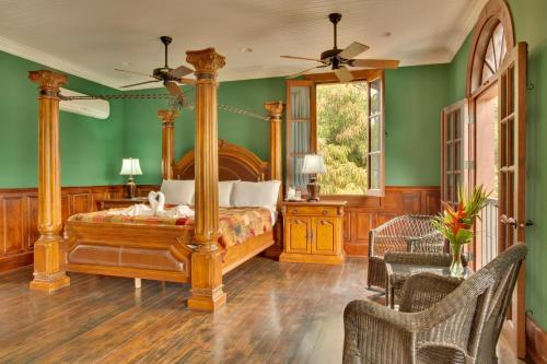 una camera con letto a baldacchino e pareti verdi di Mahogany Hall Luxury Boutique Resort a San Ignacio
