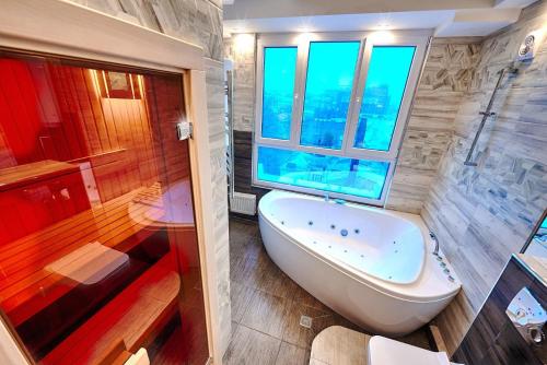 a bathroom with a tub and a shower with a window at Sauna, Big Jacuzzi , Khreshchatyk apartments in Kyiv
