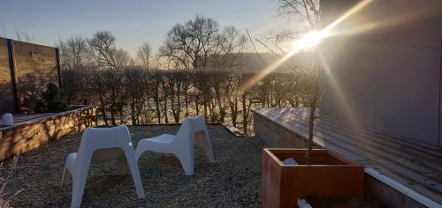two white chairs sitting on a porch with the sun shining at Wetterdelle Lodge in Heers