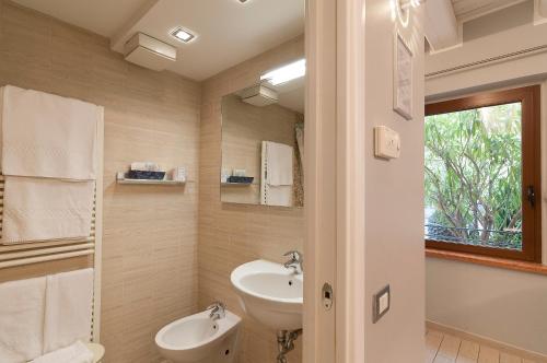 a bathroom with a sink and a toilet and a mirror at Hotel Fontana Verona in Verona