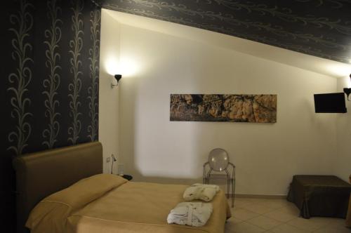 a bedroom with a bed and a painting on the wall at Regalpetra Hotel in Racalmuto