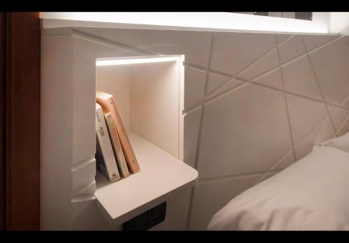 a small white shelf next to a bed in a room at Hotel Fontana Verona in Verona