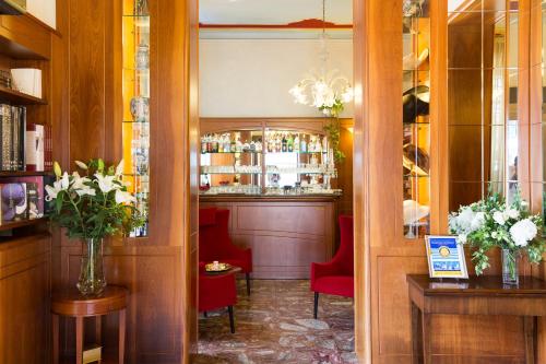 a room with a bar with red chairs at Dipendenza Hotel Londra in Alessandria