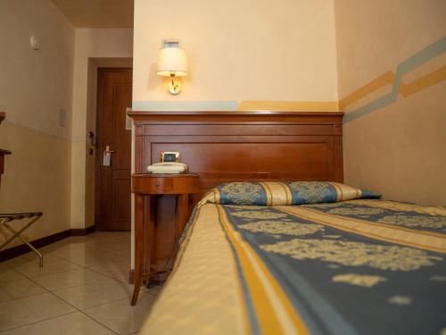 a bedroom with a bed with a wooden headboard and a telephone at Dipendenza Hotel Londra in Alessandria