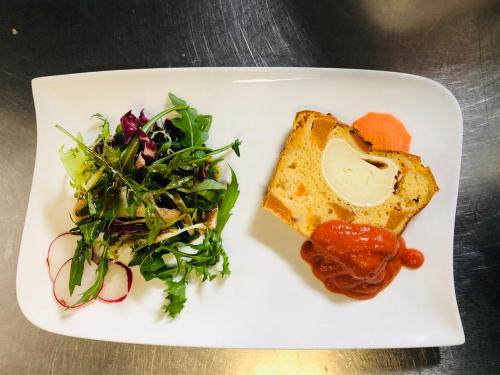 a white plate with a sandwich and a salad at Logis Hôtel Restaurant Les Aubuns in Caissargues