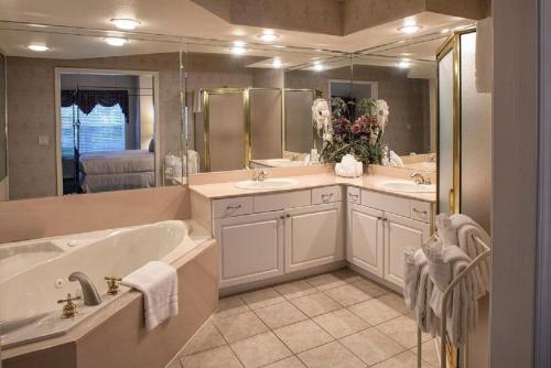 French Quarter Resort في برانسون: حمام كبير مع مغسلتين وحوض استحمام