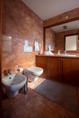 a bathroom with a sink and a toilet and a mirror at Apartament em condominio com Piscina in Matosinhos