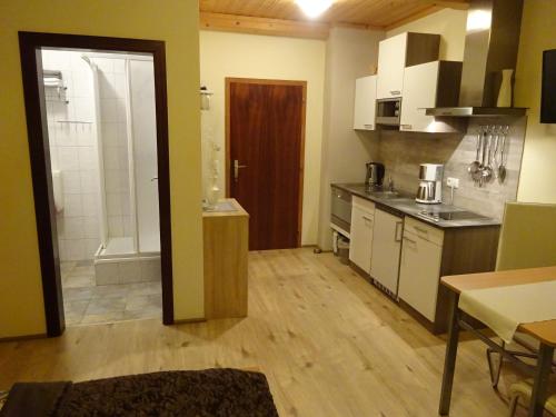 a kitchen with white cabinets and a wooden floor at Apartment zum Wasserfall in Krakaudorf