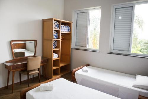 a room with two beds and a desk and a mirror at Grande Hotel Atibaia in Atibaia