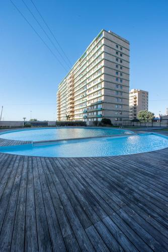 a large swimming pool with a building in the background at Apartament em condominio com Piscina in Matosinhos