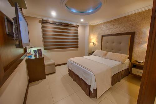 a bedroom with a bed and a flat screen tv at Hotel Veuxor in Machala