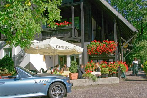 a blue car parked in front of a building with flowers at Hotel Hirschen in Glottertal
