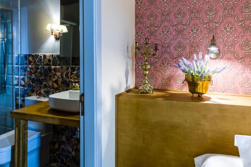 a bathroom with a sink and a vase of flowers on a counter at Hospedium Hotel El Nido de Alcudia Suites in Almodóvar del Campo