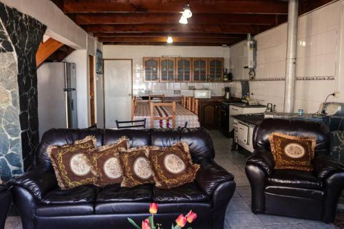 a living room with two leather couches and a kitchen at Ruca de Cura in Cobquecura