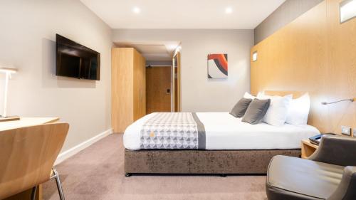 a hotel room with a bed and a tv at Holiday Inn London Luton Airport by IHG in Luton