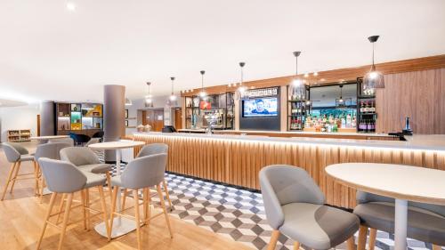 a bar in a restaurant with tables and chairs at Holiday Inn London Luton Airport by IHG in Luton