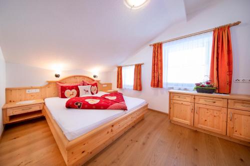 a bedroom with a wooden bed with red pillows at Ferienwohnungen Behamhof in Neukirchen am Großvenediger