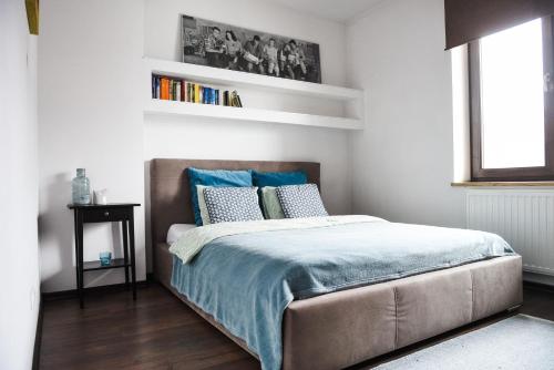 a bedroom with a bed with blue sheets and a window at Apartament Myślenice in Myślenice