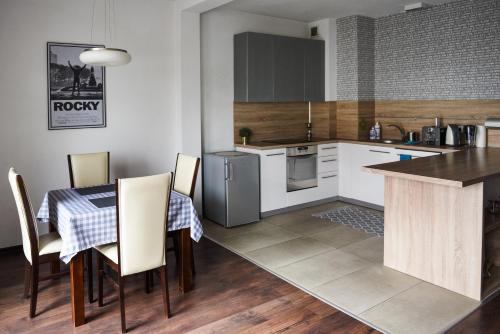 a kitchen with a table and chairs and a kitchen with white cabinets at Apartament Myślenice in Myślenice