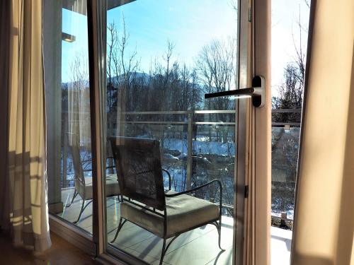a glass door with a chair on a balcony at VIP Apartamenty Stara Polana 2 in Zakopane