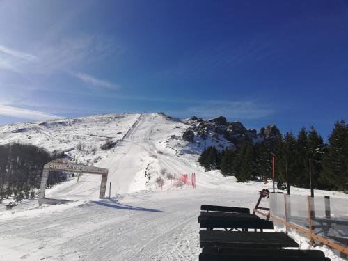 a snow covered ski slope with a bench in the foreground at Vila Vrh in Crni Vrh