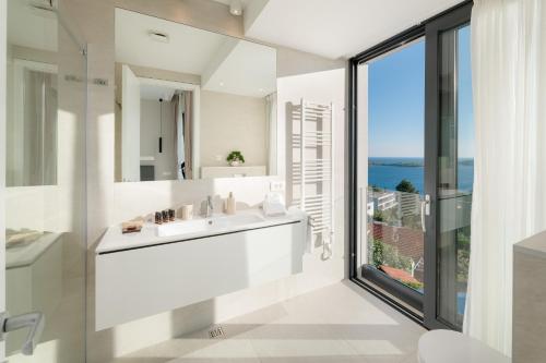a white bathroom with a sink and a large window at Villa Anabel in Hvar
