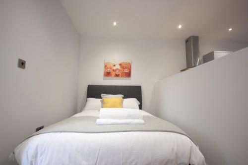 a bedroom with a bed with white sheets and yellow pillows at Studio 332 in Hull