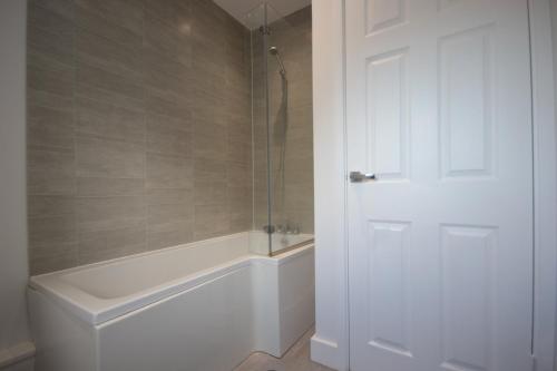 a bathroom with a shower and a tub and a white door at Studio 332 in Hull