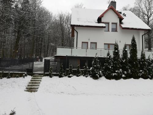 a white house with snow on the ground at Pokoje Na Szlaku in Lądek-Zdrój