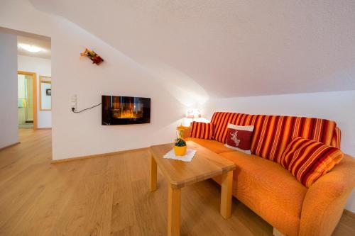 a living room with an orange couch and a table at Ferienwohnungen Behamhof in Neukirchen am Großvenediger