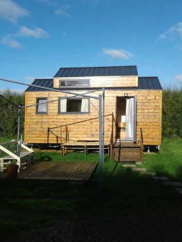 ein kleines Haus mit einem Sonnendach auf einer Terrasse in der Unterkunft Tiny house sur la Presqu'île Sauvage in Lanmodez