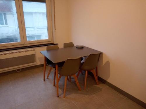 a table and chairs in a room with a window at Merlimont Plage - Paola in Merlimont