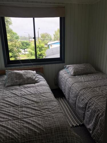 two beds in a room with a window at Mar-al Apartments in Valdivia