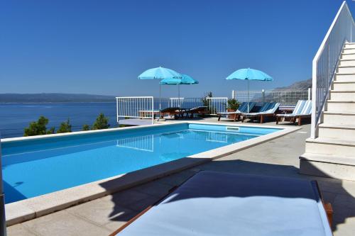 - une piscine avec des chaises et des parasols dans un bâtiment dans l'établissement Guest House Vineyard oaza, à Brela