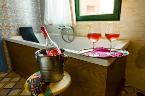 two glasses of wine sitting on a counter with a tub at Hospedium Hotel El Nido de Alcudia Suites in Almodóvar del Campo