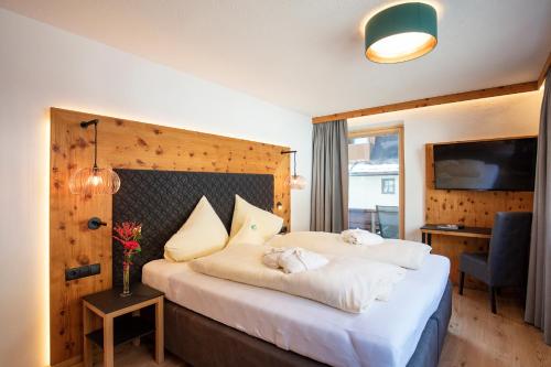 a hotel room with a large bed with white sheets at Hotel Hubertus in Sölden
