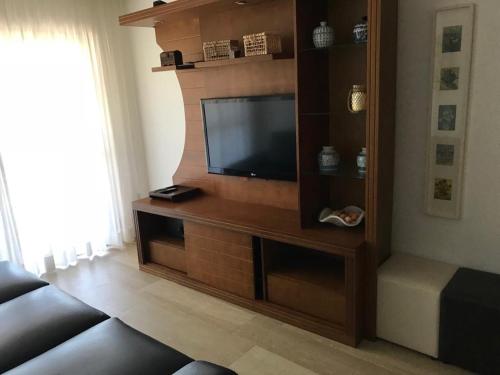 a living room with a flat screen tv on a entertainment center at Apartamento com área externa na Bacutia - uma quadra do mar in Guarapari