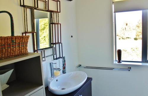 uma casa de banho com um lavatório branco e 2 janelas em The Paris Suite em Nelson