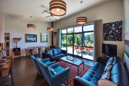 a living room with blue couches and a dining room at The Paris Suite in Nelson
