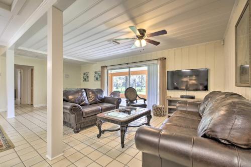 a living room with leather furniture and a flat screen tv at Rainbow River Oasis with Kayaks and Furnished Sunroom! in Dunnellon