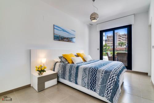 ein Schlafzimmer mit einem Bett und einem Tisch mit Blumen darauf in der Unterkunft Apartamento "VINO BLANCO" in Arenales del Sol