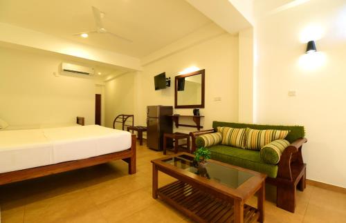a bedroom with a bed and a couch and a table at Chaaya inn Hotel in Hikkaduwa