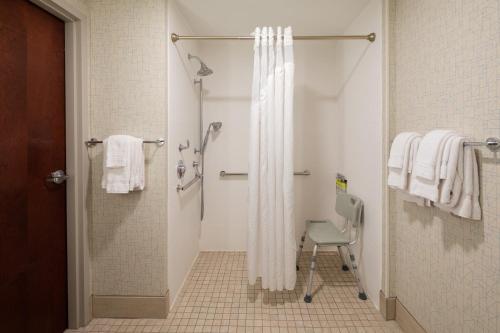 a bathroom with a shower curtain and a chair at Holiday Inn Express & Suites Bradley Airport, an IHG Hotel in Windsor Locks