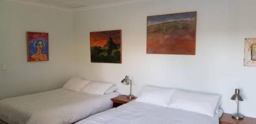 two beds in a room with paintings on the wall at Veki's Town Lodge in Mbabane