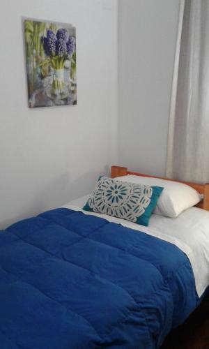 a bed with a blue blanket and a picture on the wall at Casa Vesta Mar in San Antonio