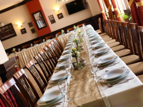 a long table with plates and glasses on it at Ambrózia Étterem és Panzió in Kazincbarcika